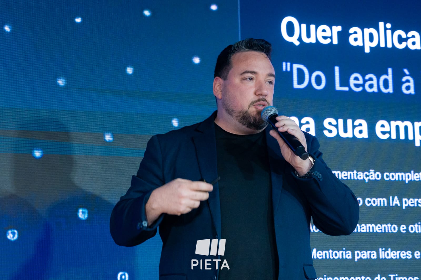 Romulo Vieira apresentando ao vivo, com microfone na mão, durante treinamento para empresários